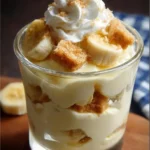 A delicious bowl of banana pudding topped with whipped cream and fresh banana slices.