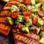 Grilled salmon fillet topped with fresh avocado salsa on a white plate