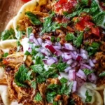 Plate of slow cooker chicken shawarma garnished with fresh vegetables and sauce.