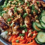 Thai-inspired peanut chicken bowl with colorful vegetables and sauce